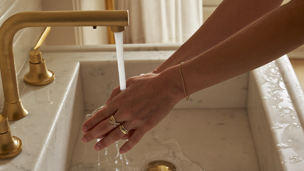 Frau wäscht ihre Hände an einem edlen Marmor-Waschbecken und trägt dabei wasserfesten Edelstahlschmuck von byLamari