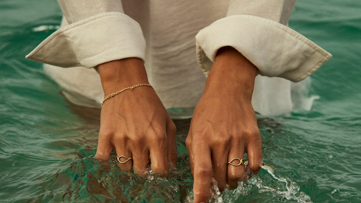 Hände mit wasserfestem Edelstahlschmuck von byLamari im klaren Meerwasser: welchen Schmuck kann man im Wasser tragen