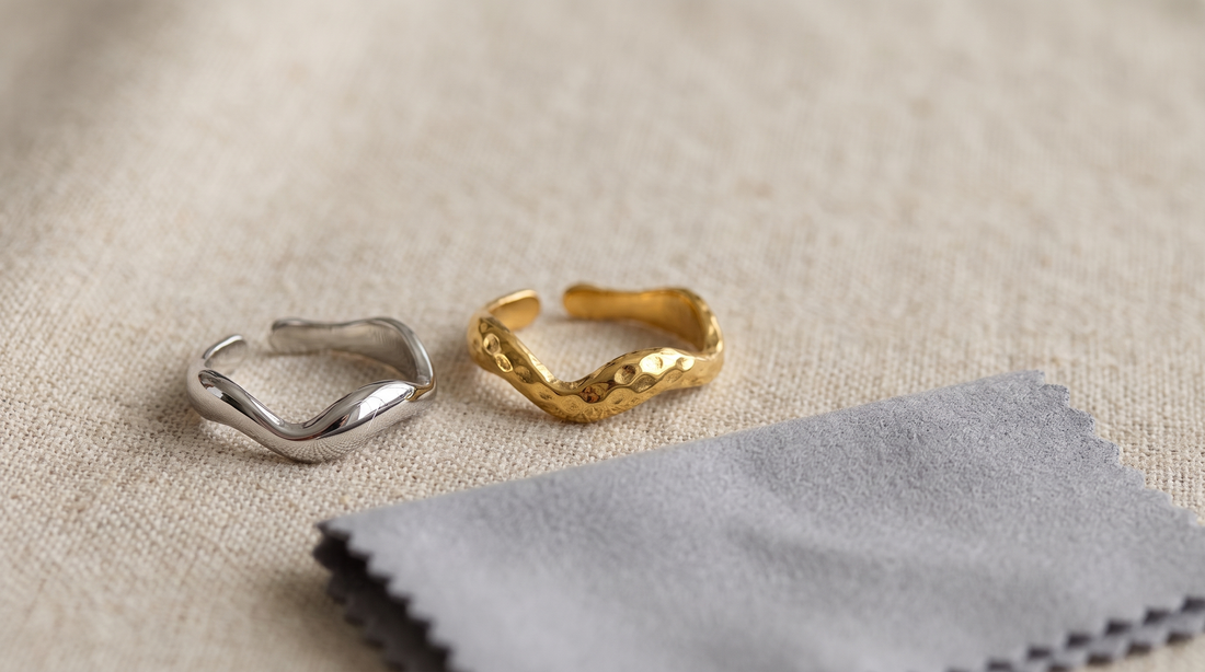 Silberfarbener polierter Ring mit feinem Kratzer neben einem goldfarbenen Ring mit gehämmerter Oberfläche