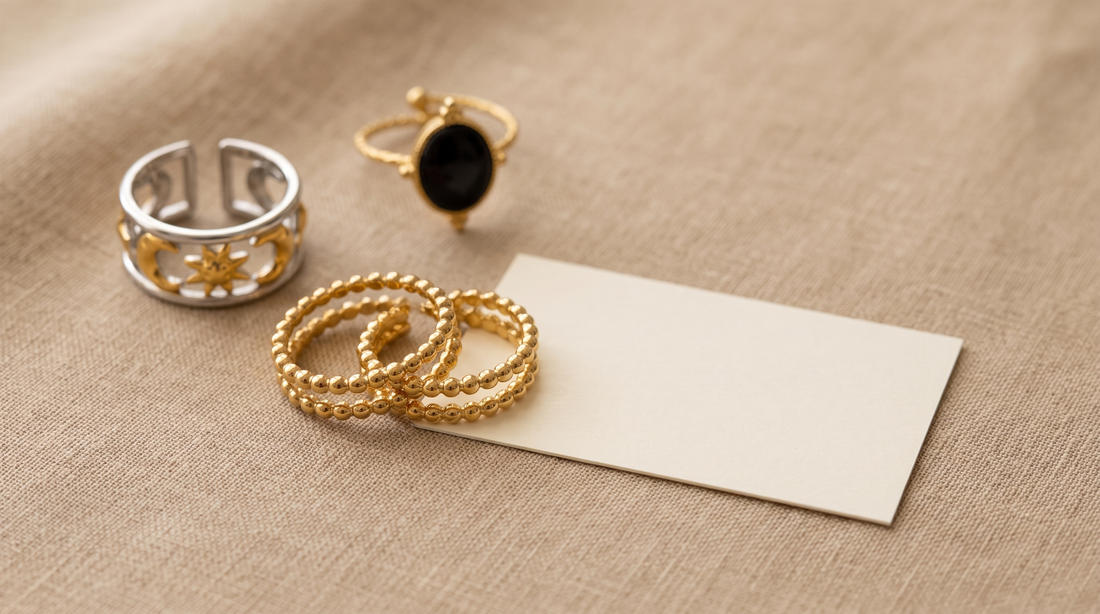 Zwei baugleiche goldfarbene Ringe liegen auf beigem Leinen neben einem leeren, unbedruckten Kärtchen