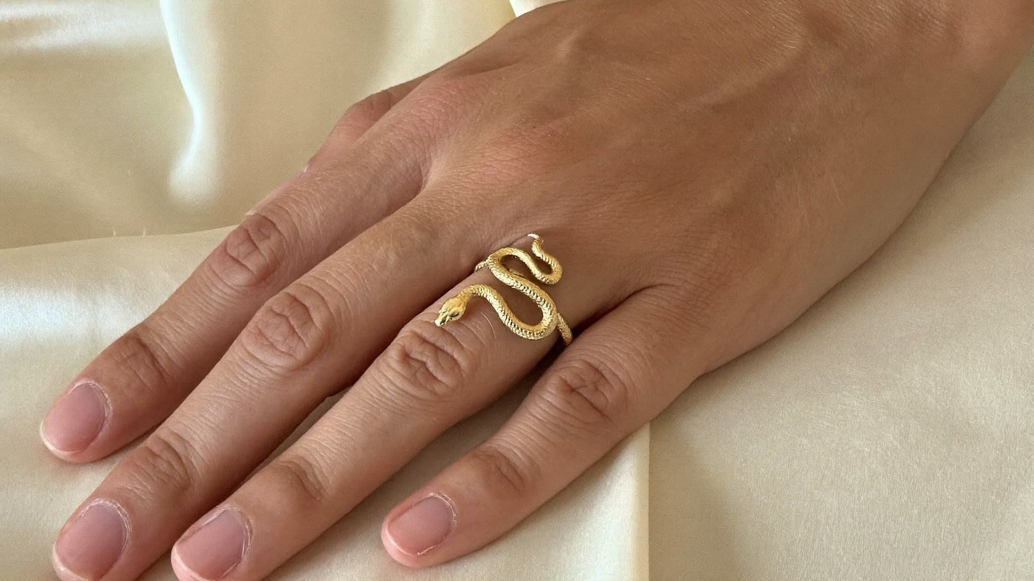 Hand mit goldenem Schlangenring aus Edelstahl von byLamari: Schlangenring Bedeutung
